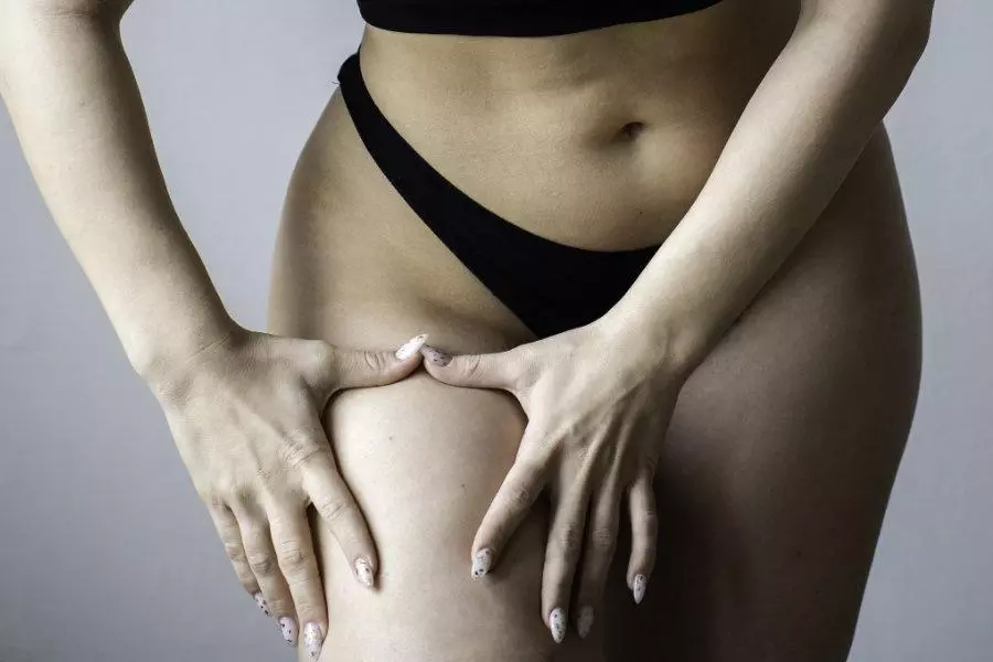 Horizontal template or header with young caucasian woman squeezing her leg with her hands to check for cellulite - Body acceptance concept - Body positive and cellulite on the thighs
